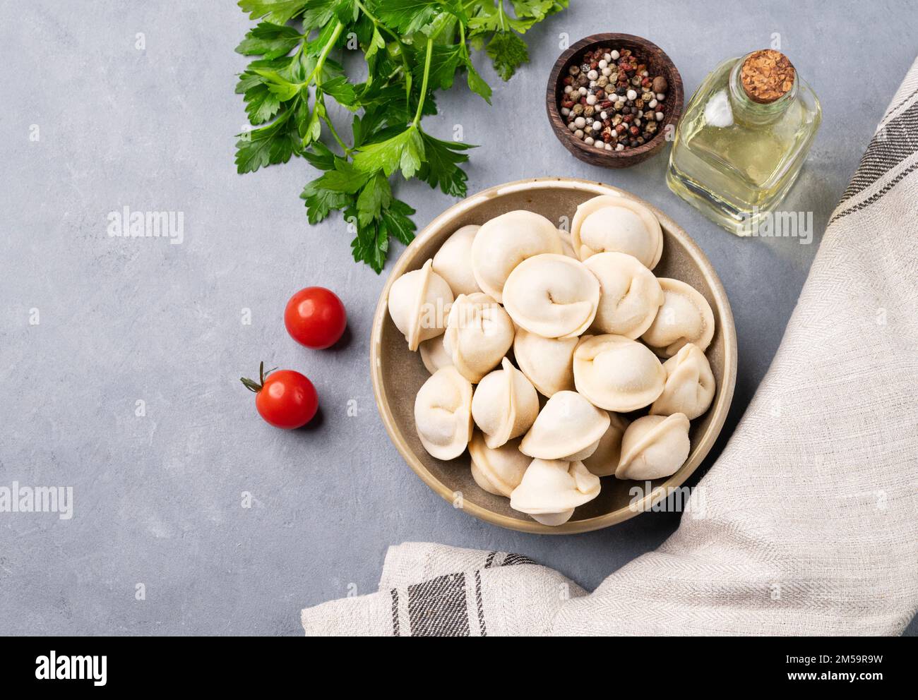 Dumplings with meat. The Russian traditional dish is Siberian pelmeni. Served with fresh herbs, butter and vegetables. Top view and copy space. Stock Photo