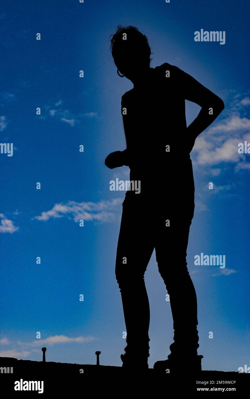 girl silhouetted against blue sky background Stock Photo