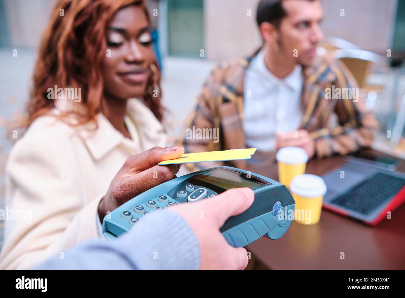 Close-up view of a woman making contactless payment with a credit card at a coffee shop. Stock Photo