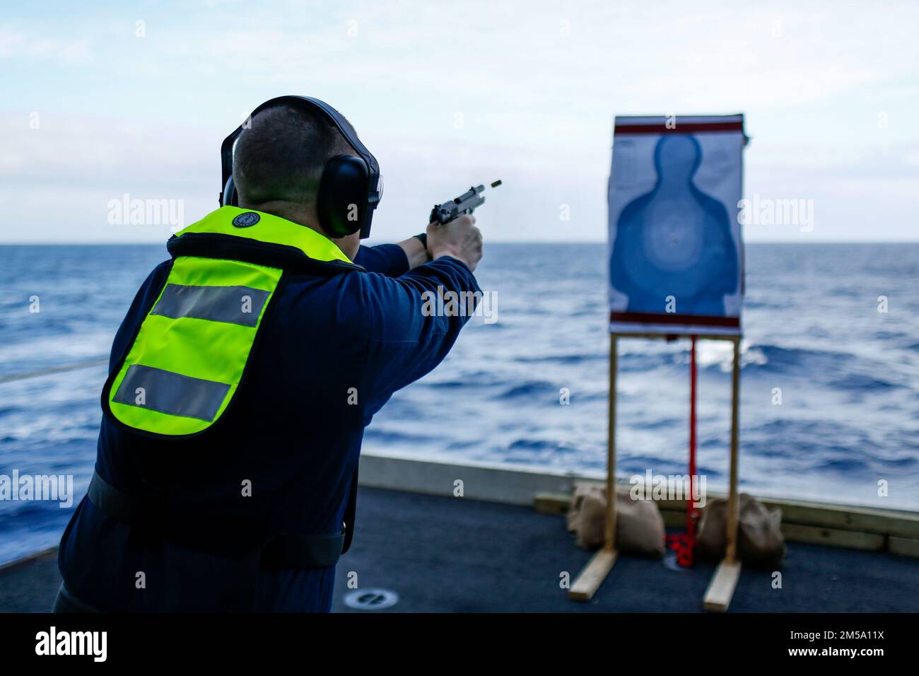 PHILIPPINE SEA (Feb. 13, 2022) Senior Chief Information Systems Technician John Shubert, from Wakeeney, Kan., fires an M9 service pistol during a weapons qualification aboard the Nimitz-class aircraft carrier USS Abraham Lincoln (CVN 72). Abraham Lincoln Strike Group is on a scheduled deployment in the U.S. 7th Fleet area of operations to enhance interoperability through alliances and partnerships while serving as a ready-response force in support of a free and open Indo-Pacific region. Stock Photo