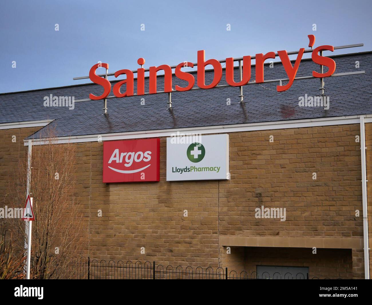 Orange Sainsburys roof sign red Argos and white Lloyds pharmacy sign on building wall Stock Photo