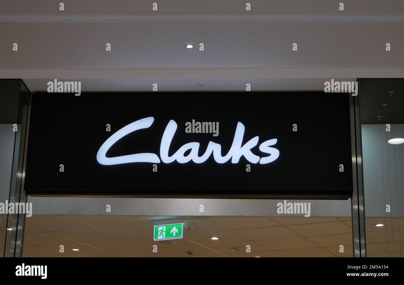 Black sign with white letters saying clarks and small green sign with running man Stock Photo