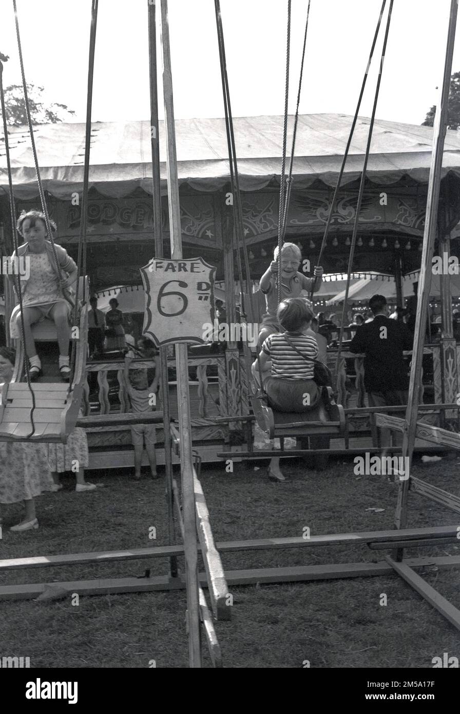 1950s, historical, young children on a swing ride at a funfair, price of ride 6D, England, UK. Stock Photo