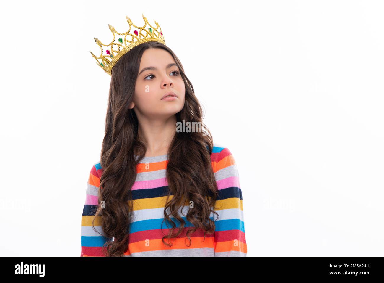 Portrait of ambitious teenage girl with crown, feeling princess, confidence. Child princess crown on isolated studio background. Serious teenager girl Stock Photo