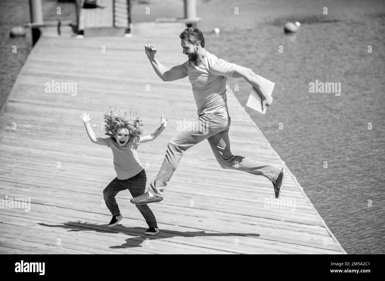 Feel free to jump. Energetic father and son jump on pier. Family fun