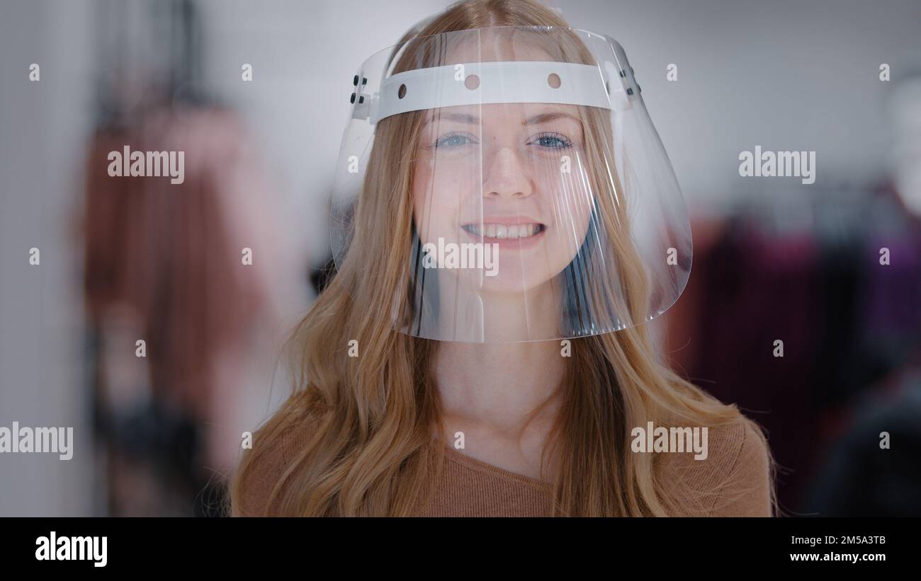 Headshot portrait girl in transparent plastic mask close-up young caucasian woman smiling looking at camera protection from infection coronavirus Stock Photo