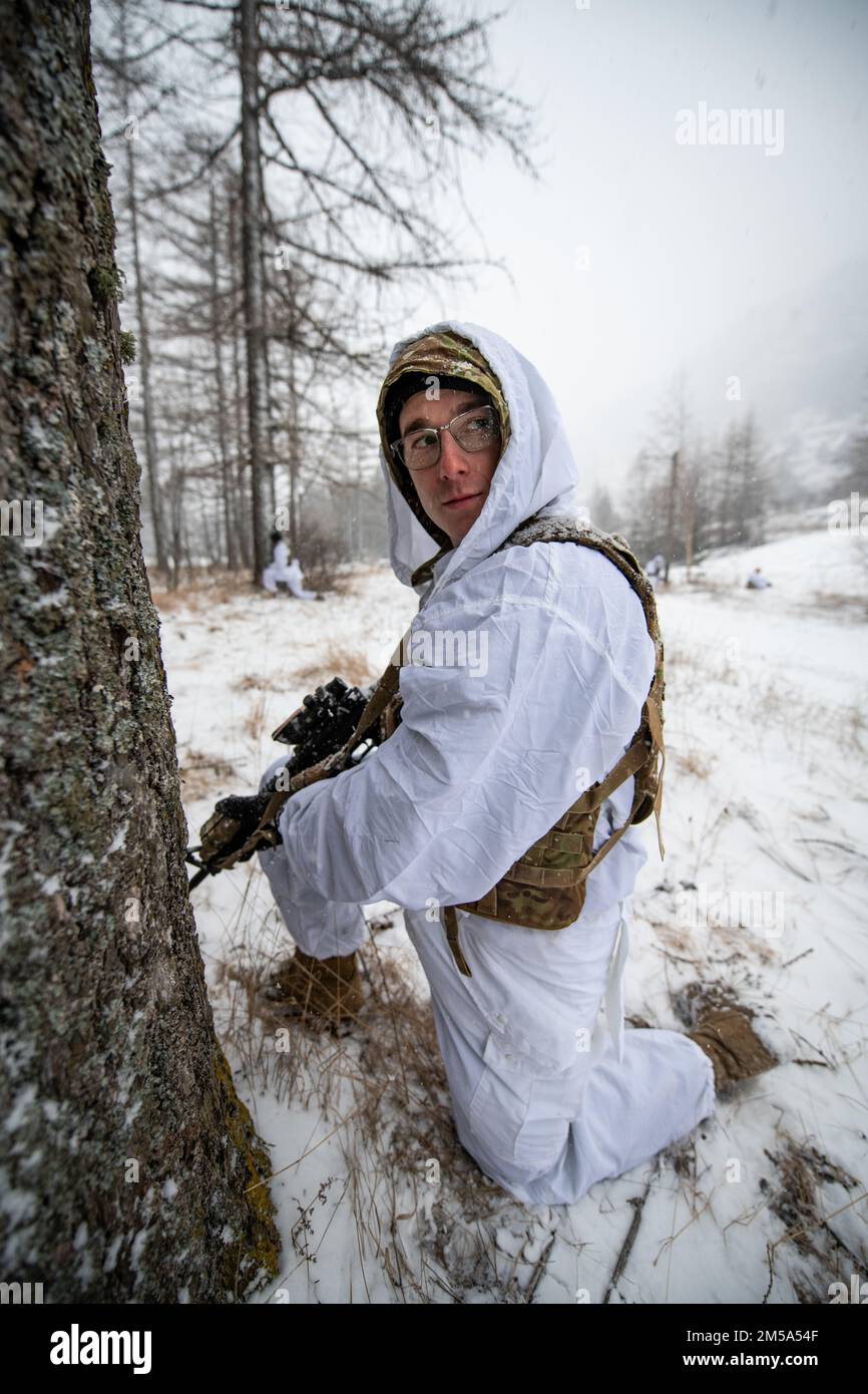 A U.S. Army paratrooper assigned to 1st Battalion, 503rd Parachute Infantry Regiment looks to his leadership for a signal while providing security during a patrol while conducting an integrated procedure familiarization alongside Italian soldiers from the 3rd Alpini Regiment. This training is part of Exercise Steel Blizzard at Pian dell’Alpe in Usseaux, Italy on Feb. 14, 2022.     Exercise Steel Blizzard is an Italian Army-hosted multinational mountain and arctic warfare training exercise. Three reconnaissance platoons from the 173rd Airborne Brigade take part in a three-phase training regimen Stock Photo