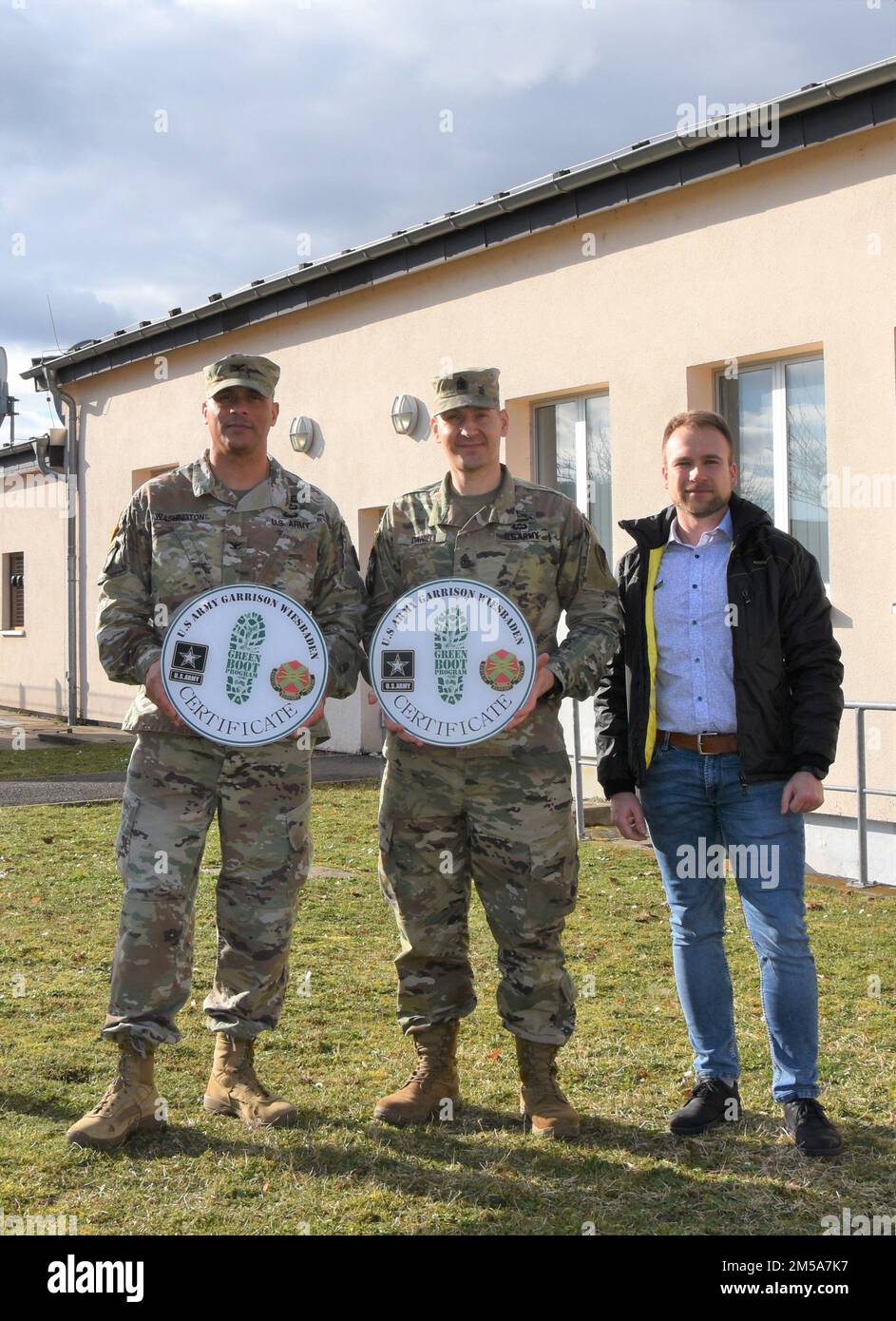 USAG Wiesbaden Commander Col. Mario Washington presents Green Boot Program signs to Headquarters and Headquarters Battalion, U.S. Army Europe-Africa, Battalion Command Sgt. Maj. Joseph Daniel, along with Tomasz Filatow, Energy Manager with the Garrison’s Directorate of Public Works. Stock Photo