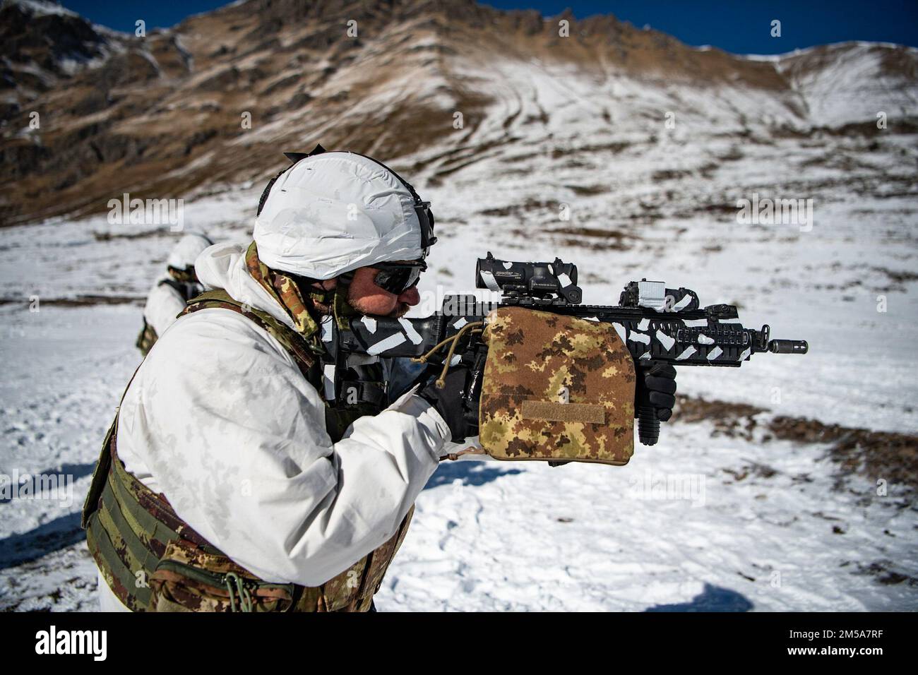 An Italian soldier from the 3rd Alpini Regiment provides covering fire for his team during an integrated marksmanship range alongside U.S. Army paratroopers assigned to the 173rd Airborne Brigade. This training is part of Exercise Steel Blizzard at Pian dell’Alpe in Usseaux, Italy on Feb. 15, 2022.     Exercise Steel Blizzard is an Italian Army-hosted multinational mountain and arctic warfare training exercise. Three reconnaissance platoons from the 173rd Airborne Brigade take part in a three-phase training regimen with the 3rd Alpini Regiment to expand force capabilities by learning how to sh Stock Photo
