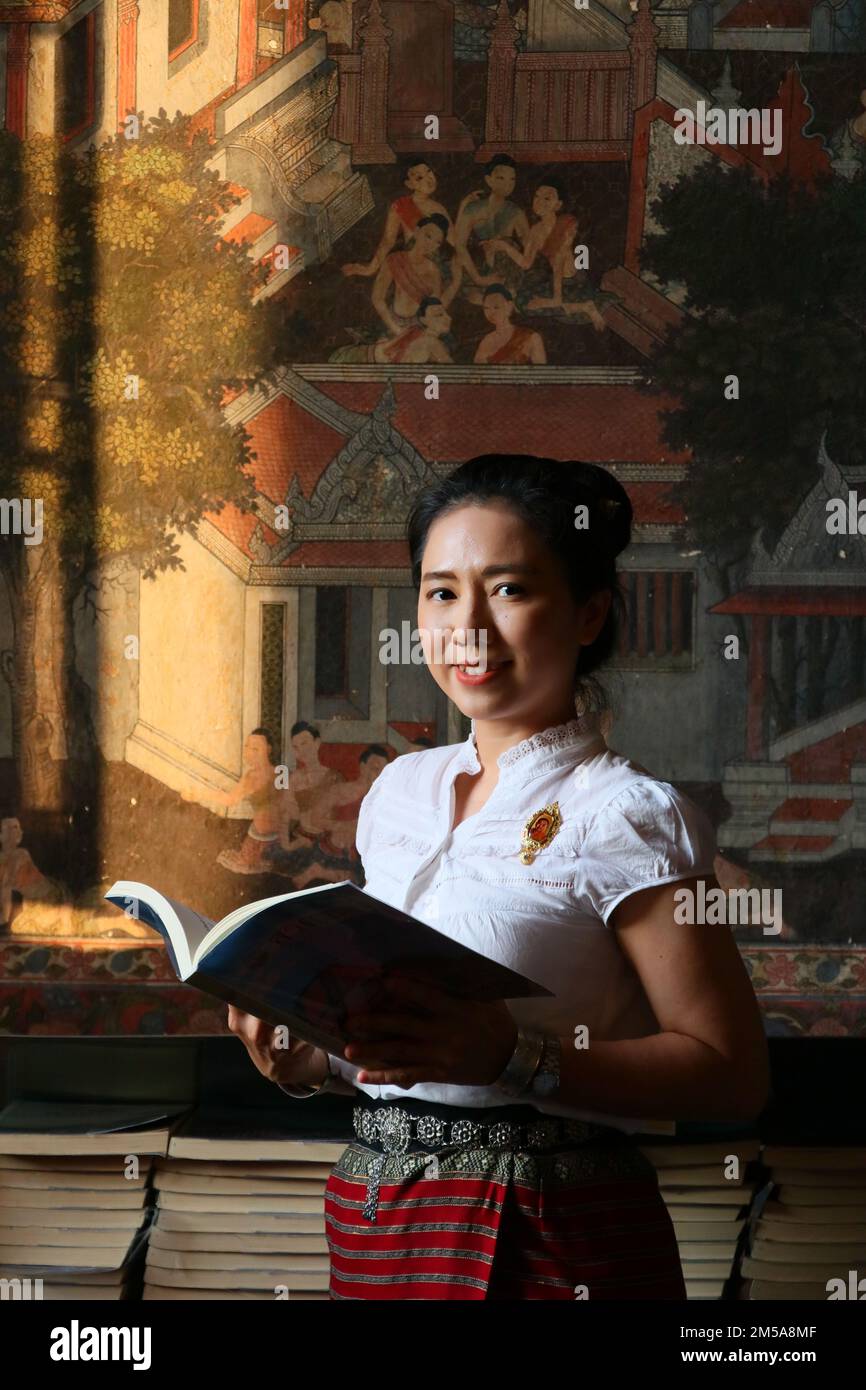 Thai lady in Thai costume read book in Thai painting background Stock Photo