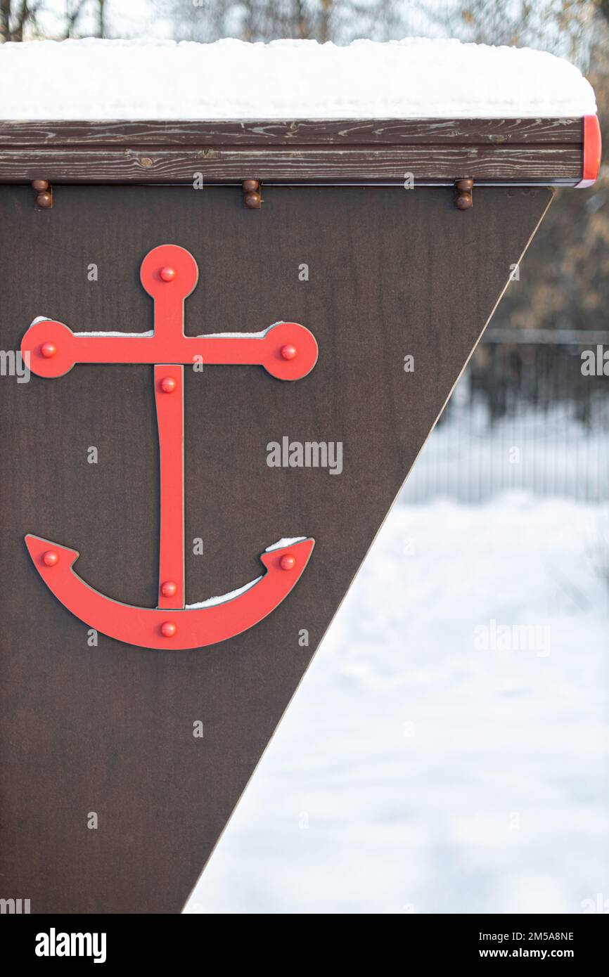 decorative anchor of red color on the wall on the street. anchor symbol Stock Photo