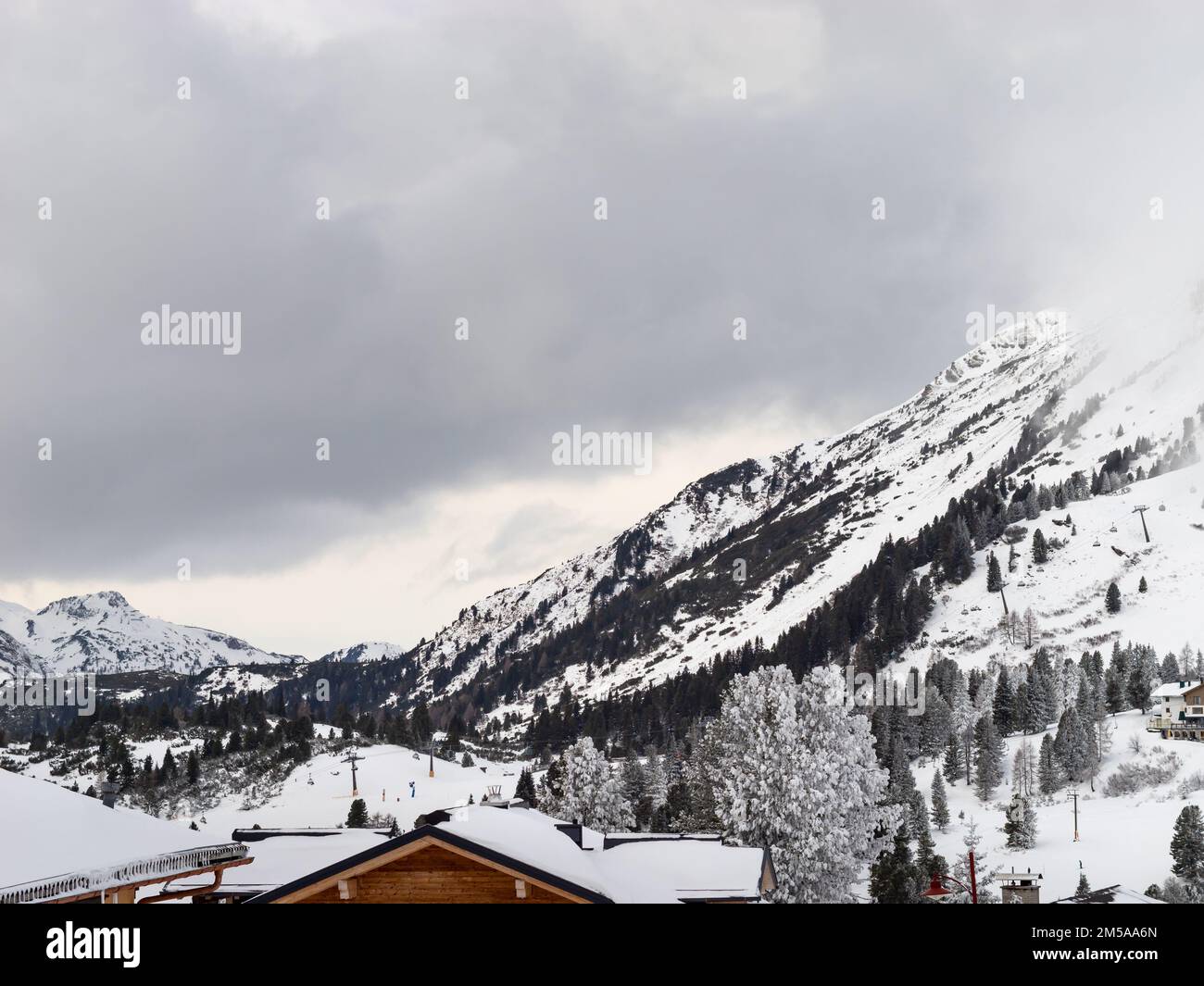 Landscape of a winter sport resort in Austria. Snowy mountains in the nature. Coniferous trees are part of the alpine vegetation. People are skiing. Stock Photo