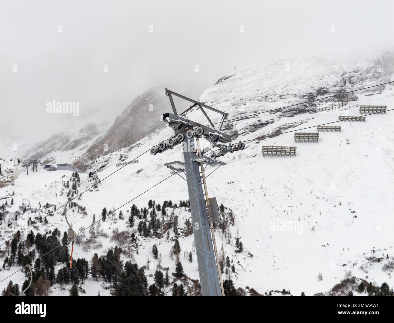 Pole of a ski lift with steel cables and pulley wheels. The wheels are guiding the cables to ensure a hight over the ground. The support is required. Stock Photo