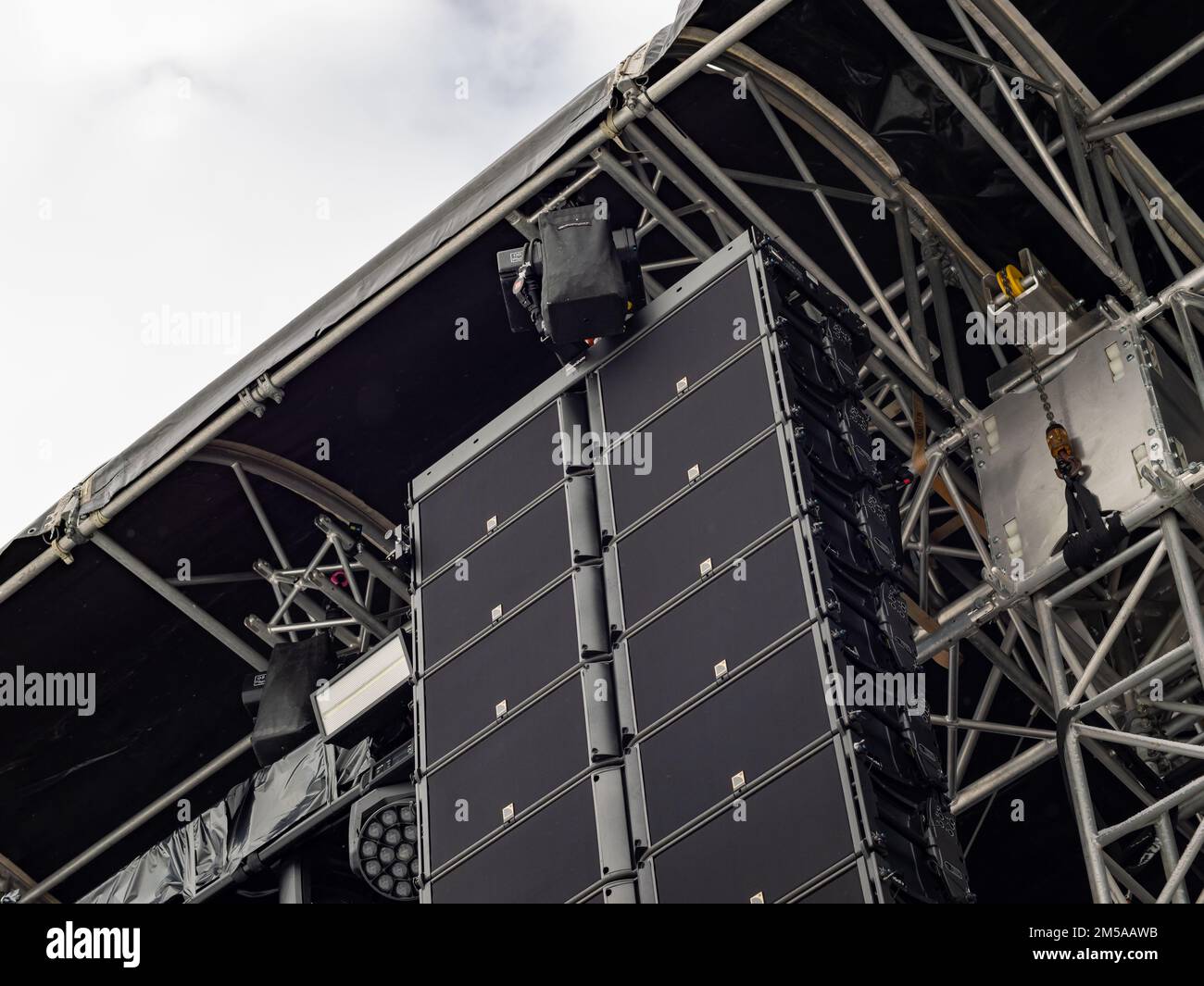 Line array loudspeaker of a concert stage. Professional equipment for a live music gig. The speakers are mounted to a frame construction. Stock Photo