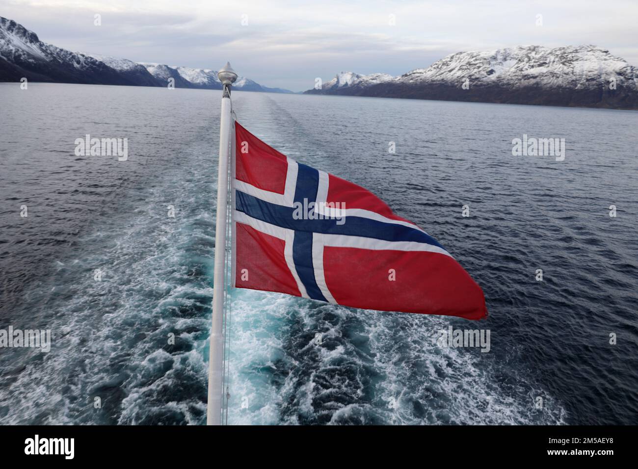 Flag of Norway waving in the wind on the stern of a ship against a blue ...