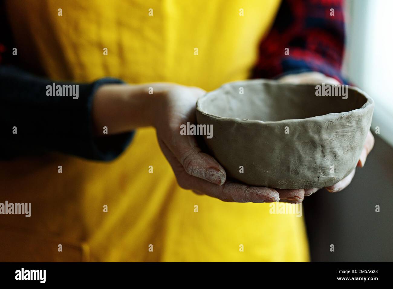 Woman potter in apron molding clay bowl.Hands of professional ceramist