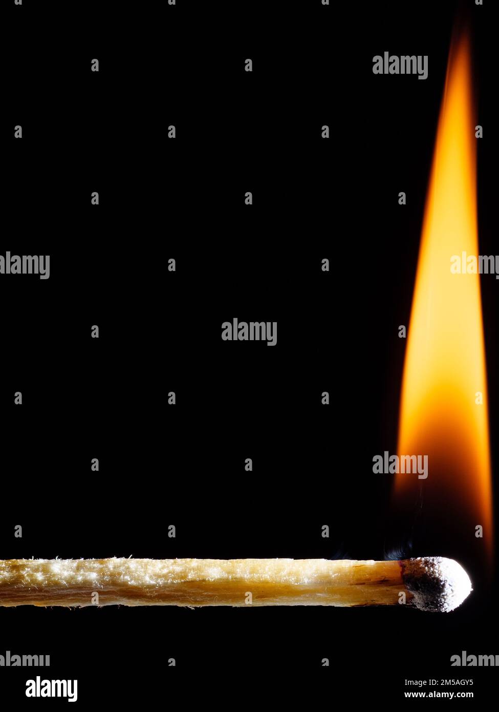 Wooden match burns with an orange flame against a black background ...