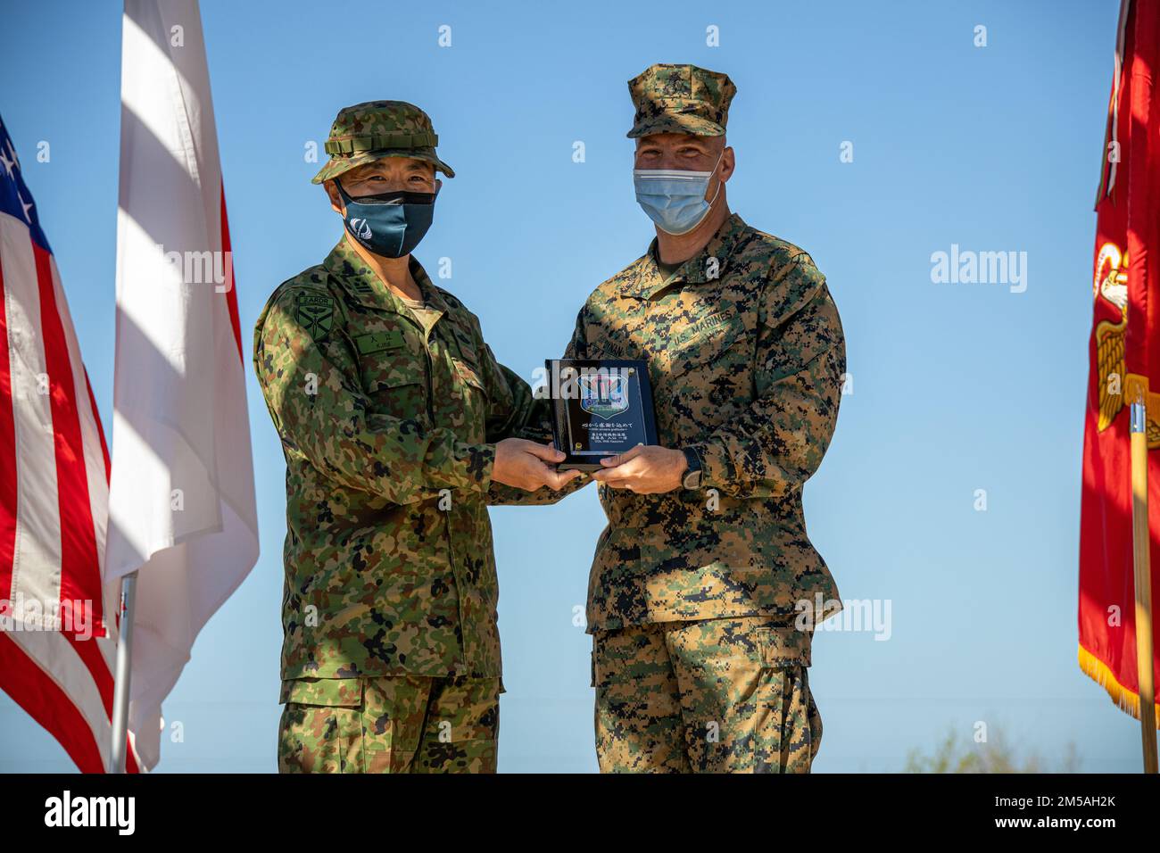 Japan Ground Self-Defense Force (JGSDF) Col. Kazuhiro Irie, commanding officer of the 2nd Amphibious Rapid Deployment Regiment, left, gifts a plaque in honor of exercise Iron Fist 2022 to U.S. Marine Corps Col. Sean Dynan, commanding officer of the 15th Marine Expeditionary Unit during the closing ceremony at Marine Corps Base Camp Pendleton, California, Feb. 16, 2022. For almost two decades the U.S. Marine Corps, U.S. Navy, and JGSDF have conducted exercise Iron Fist, training together in amphibious operations and affirming the U.S. commitment to our allies. Stock Photo