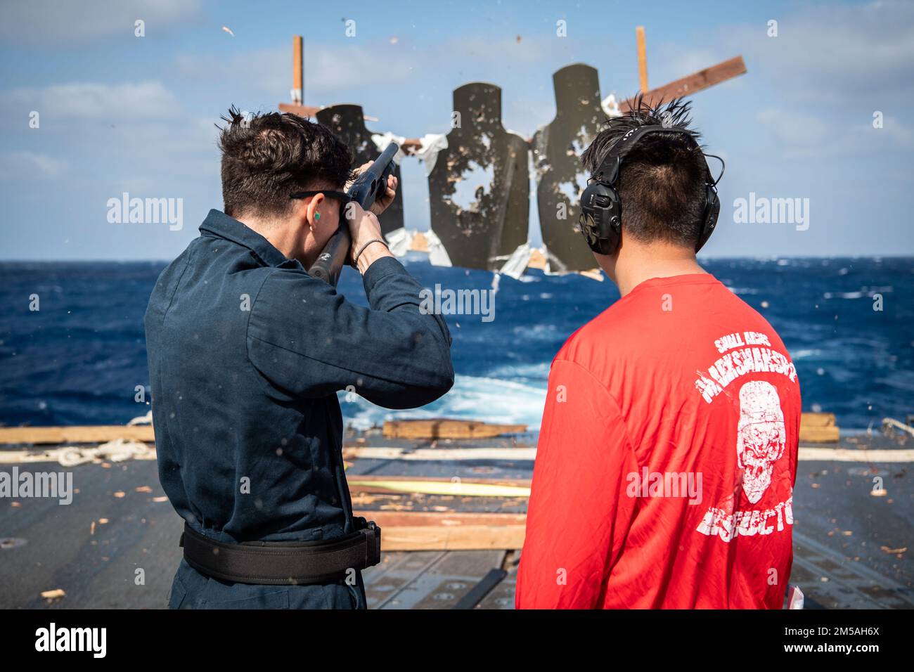 SOUTH CHINA SEA (Feb. 16, 2022) Gunner’s Mate 2nd Class Jeremy Gillentine, right, from Abilene, Texas, acts as Range Safety Officer while Gunner’s Mate Seaman Cade Kevek, from Union Grove, Wisconsin, fires the M500 shotgun during a qualification course aboard the Arleigh Burke-class guided-missile destroyer USS Dewey (DDG 105). Dewey is assigned to Destroyer Squadron (DESRON) 15 and is underway supporting a free and open Indo-Pacific. CTF 71/DESRON 15 is the Navy’s largest forward-deployed DESRON and the U.S. 7th Fleet’s principal surface force. Stock Photo