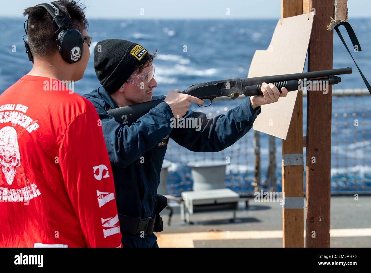 SOUTH CHINA SEA (Feb. 16, 2022) Gunner’s Mate 2nd Class Jeremy Gillentine, left, from Abilene, Texas, acts as Range Safety Officer while Sonar Technician (Surface) 2nd Class Taylor Clark, from Arlington, Texas, fires the M500 shotgun during a qualification course aboard the Arleigh Burke-class guided-missile destroyer USS Dewey (DDG 105). Dewey is assigned to Destroyer Squadron (DESRON) 15 and is underway supporting a free and open Indo-Pacific. CTF 71/DESRON 15 is the Navy’s largest forward-deployed DESRON and the U.S. 7th Fleet’s principal surface force. Stock Photo