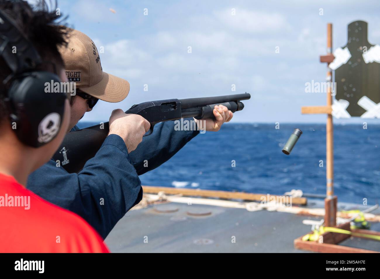 SOUTH CHINA SEA (Feb. 16, 2022) Gunner’s Mate 2nd Class Jeremy Gillentine, left, from Abilene, Texas, acts as Range Safety Officer while Fire Controlman (Aegis) 3rd Class Ulysses Mendoza, from Port St. Lucie, Florida, fires the M500 shotgun during a qualification course aboard the Arleigh Burke-class guided-missile destroyer USS Dewey (DDG 105). Dewey is assigned to Destroyer Squadron (DESRON) 15 and is underway supporting a free and open Indo-Pacific. CTF 71/DESRON 15 is the Navy’s largest forward-deployed DESRON and the U.S. 7th Fleet’s principal surface force. Stock Photo