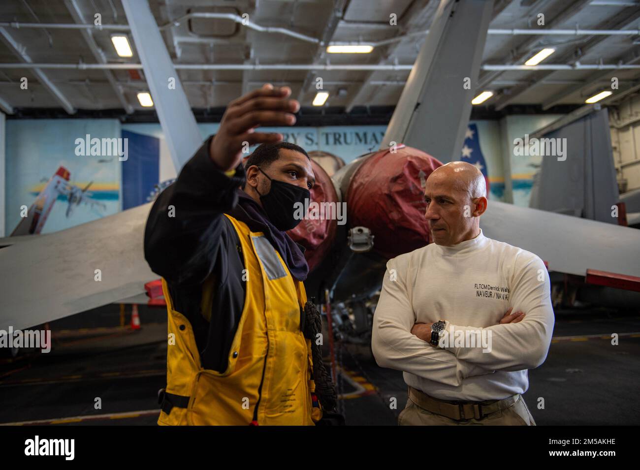 220216-N-ZE328-1250 MEDITERRANEAN SEA (Feb. 16, 2022) Fleet Master Chief Derrick Walters, fleet master chief of U.S. Naval Forces Europe and Africa, right, speaks with Aviation Boatswain's Mate (Handling) 2nd Class Isaac Willabustner, from Nashville, Tennessee, in the hangar bay of the Nimitz-class aircraft carrier USS Harry S. Truman (CVN 75), Feb. 16, 2022. The Harry S. Truman Carrier Strike Group is on a scheduled deployment in the U.S. Sixth Fleet area of operations in support of naval operations to maintain maritime stability and security, and defend U.S., allied and partner interests in Stock Photo