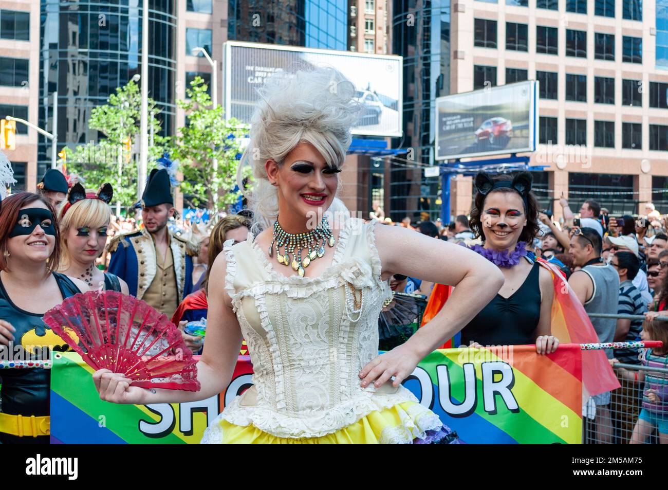 A drag queen walks in Bloor St. leading a group of people. She is part of the annual event celebrating the LGBTQ+ community in the city. Stock Photo