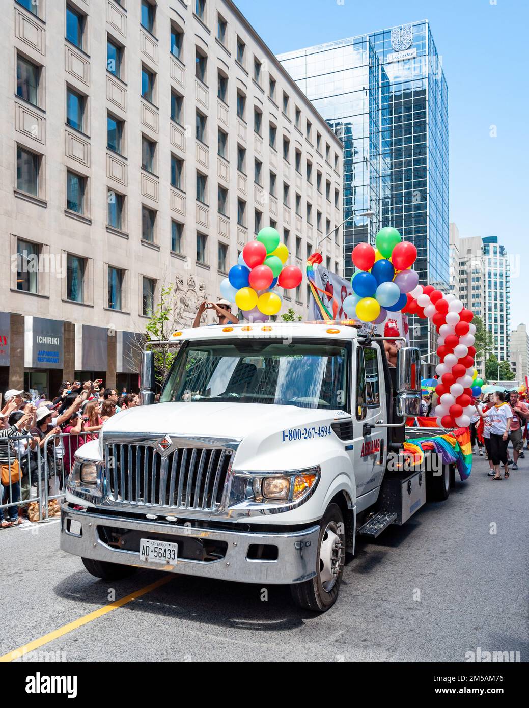 A truck decorated with rainbow color balloons drive in Bloor St. The vehicle is part of the LGBTQ+ annual celebration in the downtown district. Stock Photo