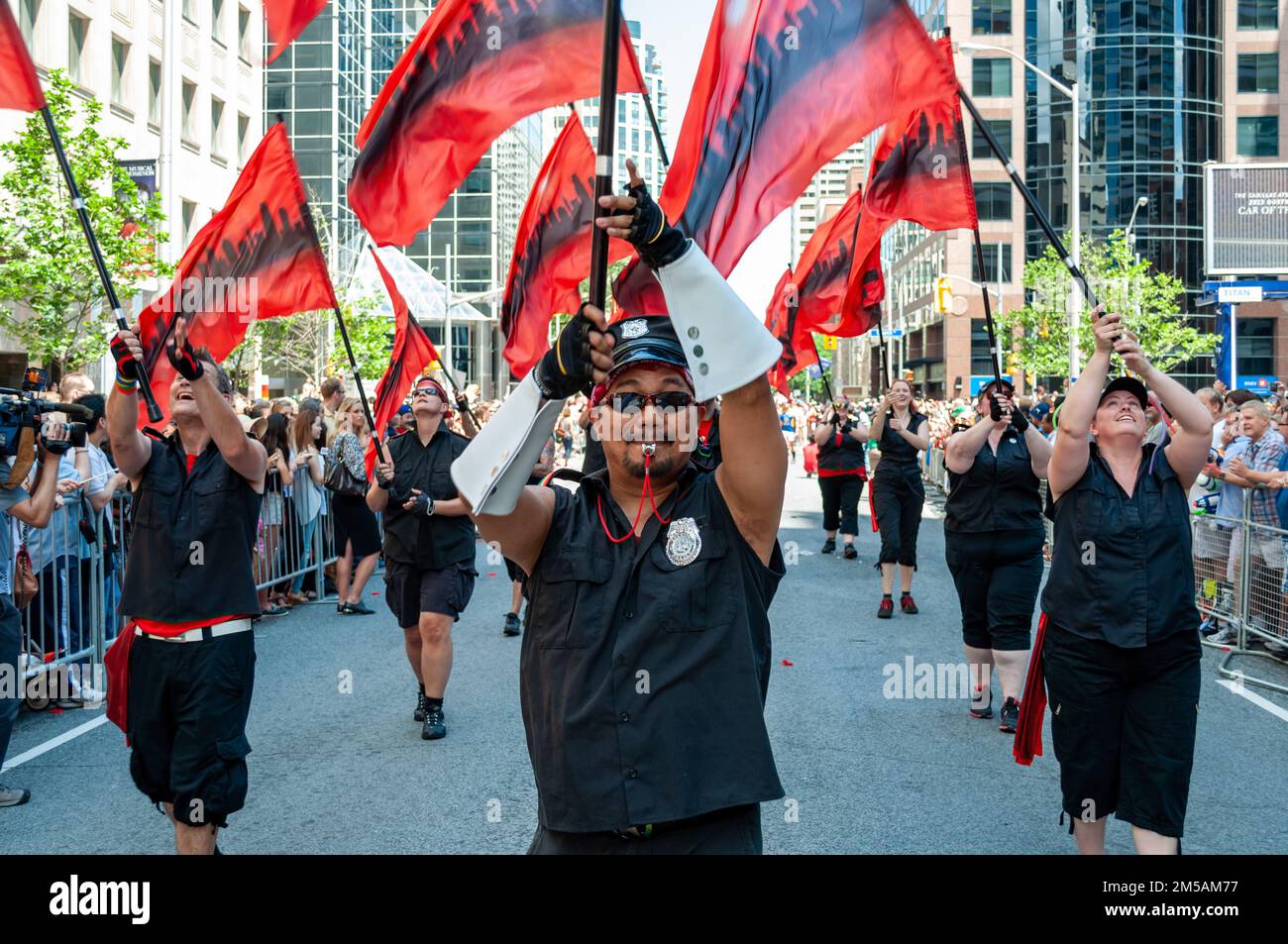 A group of people with red and black flags marches as part of the annual LGBTQ+ annual celebration. Symmetric view. Stock Photo