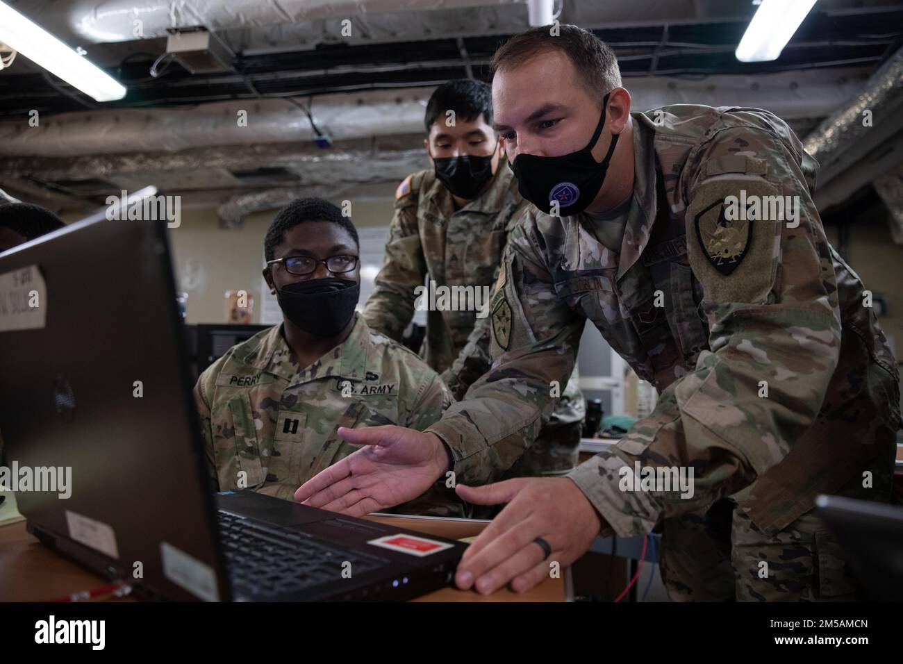 U.S. Army Cpt. Nathaniel Perry, left, a Field Artillery Officer and Sgt. Jimmy Nguyen, middle, a Signal Operations Support Specialist, both assigned to America’s First Corps and U.S. Air Force Staff Sgt. Matthew Joblin, right, a Joint Communications Technician assigned to Joint Communications Support Element, set up a communication line on the USNS City of Bismarck at Naval Base Guam, Feb. 16, 2022. Service members are testing communication abilities to enhance readiness, showcase joint interoperability and exercise distributed mission command in the Pacific. Stock Photo