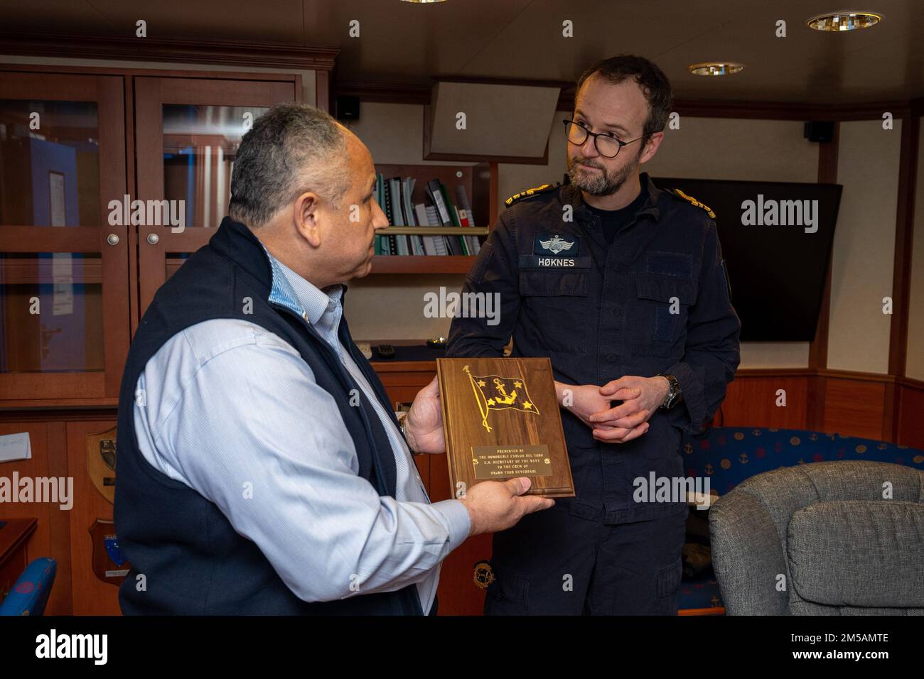 BERGEN, Norway (Feb. 16, 2022) — Secretary of the Navy Carlos Del Toro presents a plaque to Norwegian Cmdr. Lars Ole Høknes, commanding officer of HNoMS Thor Heyerdahl (F314), aboard the ship in Bergen, Norway, Feb. 16, 2022. Secretary Del Toro is in Norway to visit U.S. service members and Norwegian government leaders to reinforce existing bilateral and multilateral security relationships between the U.S. Navy and the Royal Norwegian Navy. Stock Photo