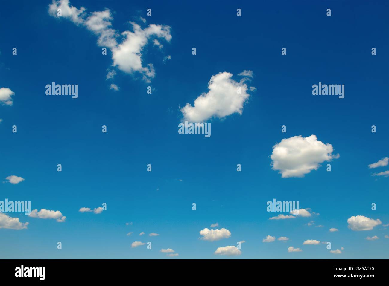 White fluffy clouds and bright sun on dark blue sky. Stock Photo