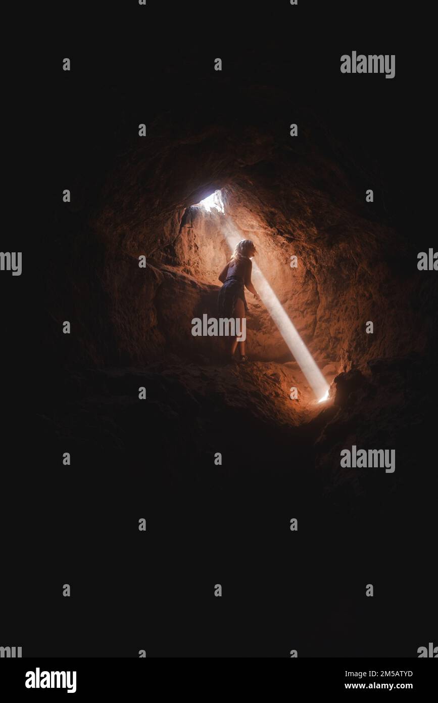 girl exploring a cave with a light beam Stock Photo