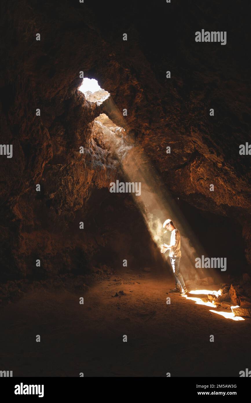 Man exploring cave with light beam Stock Photo