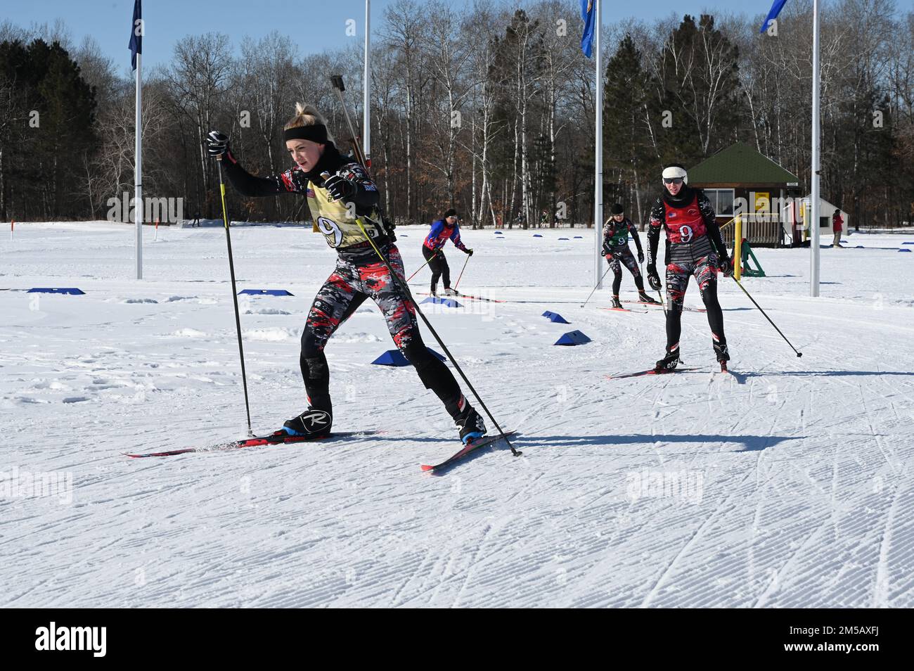 U.S. Army 2nd Lt. Kaitlyn Gura, of the 1,188th Air Defense Artillery Regiment, North Dakota Army National Guard, leads her three-person team through the penalty area of the biathlon patrol race at the Chief of the National Guard Bureau Biathlon Championship held at Camp Ripley, Minn., Feb. 11-17, 2022. Spc. Sydney Kautz, of the 188th Engineer Company, and Senior Master Sgt. Danelle Card, of the 119th Wing are following her through the course. The three-member North Dakota team contributed to a second place finish in the women’s overall category of the competition with several individual and gr Stock Photo
