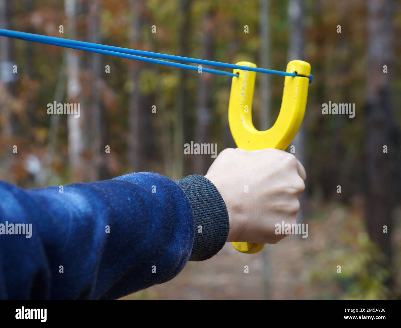 slingshot with a stretched bowstring in a female hand against the