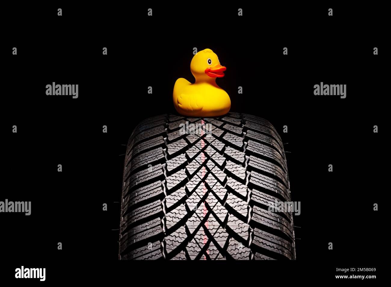 Winter car tire for snow and yellow rubber duck toy isolated on white background Stock Photo