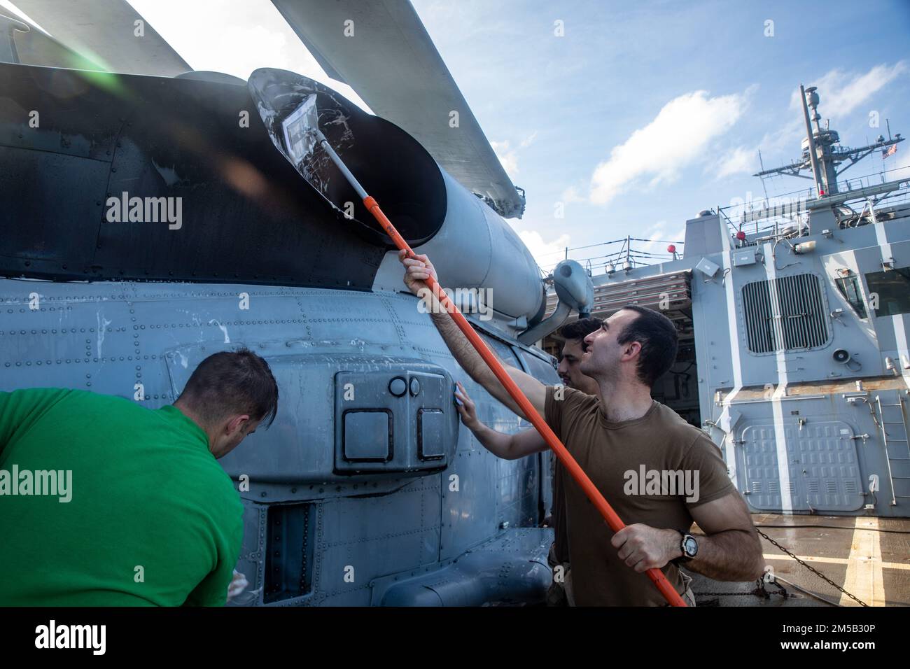 SOUTH CHINA SEA (Feb. 17, 2022) Sailors scrub down an MH-60R helicopter aboard Arleigh Burke-class guided-missile destroyer USS Ralph Johnson (DDG 114). Ralph Johnson is assigned to Task Force 71/Destroyer Squadron (DESRON) 15, the Navy’s largest forward-deployed DESRON and the U.S. 7th fleet’s principal surface force. Stock Photo