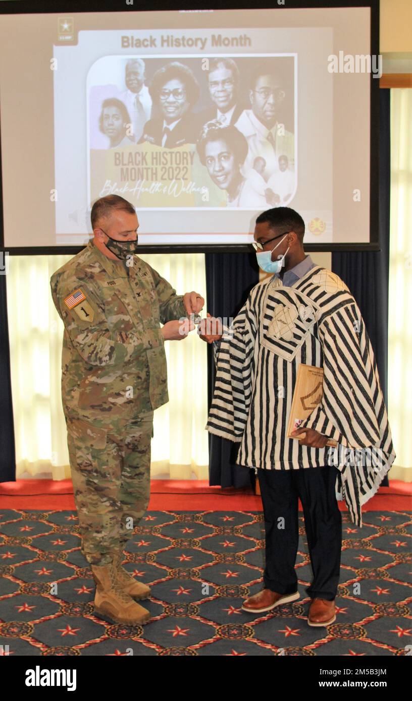 Garrison Commander Col. Michael Poss presents Momolu Sonie with the Tomah Veterans Affairs Medical Center with a a Commander’s Coin for Excellence on Feb. 17, 2022, during the 2022 Fort McCoy Black History Month observance in McCoy's Community Center at Fort McCoy, Wis. Sonie was one of two speakers for the event. The observance combined the January observance for Martin Luther King Jr. Day, which was canceled at the last minute, and the February observance for Black History Month. The observance was coordinated by the Fort McCoy Equal Opportunity Office. For more information about Black Histo Stock Photo