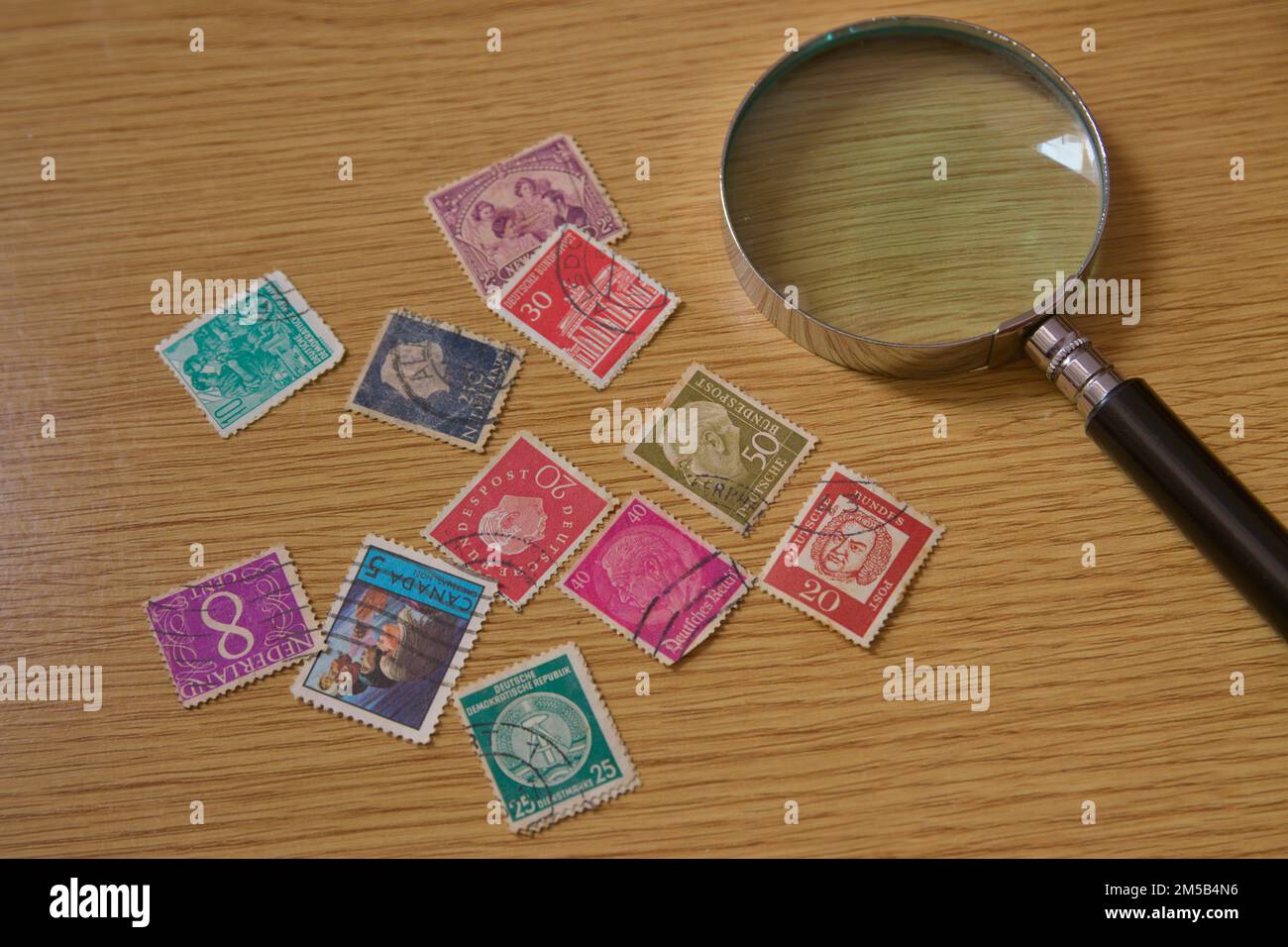 Flat lay of some old stamps from different countries of the world next to a magnifying glass for a philately fan Stock Photo