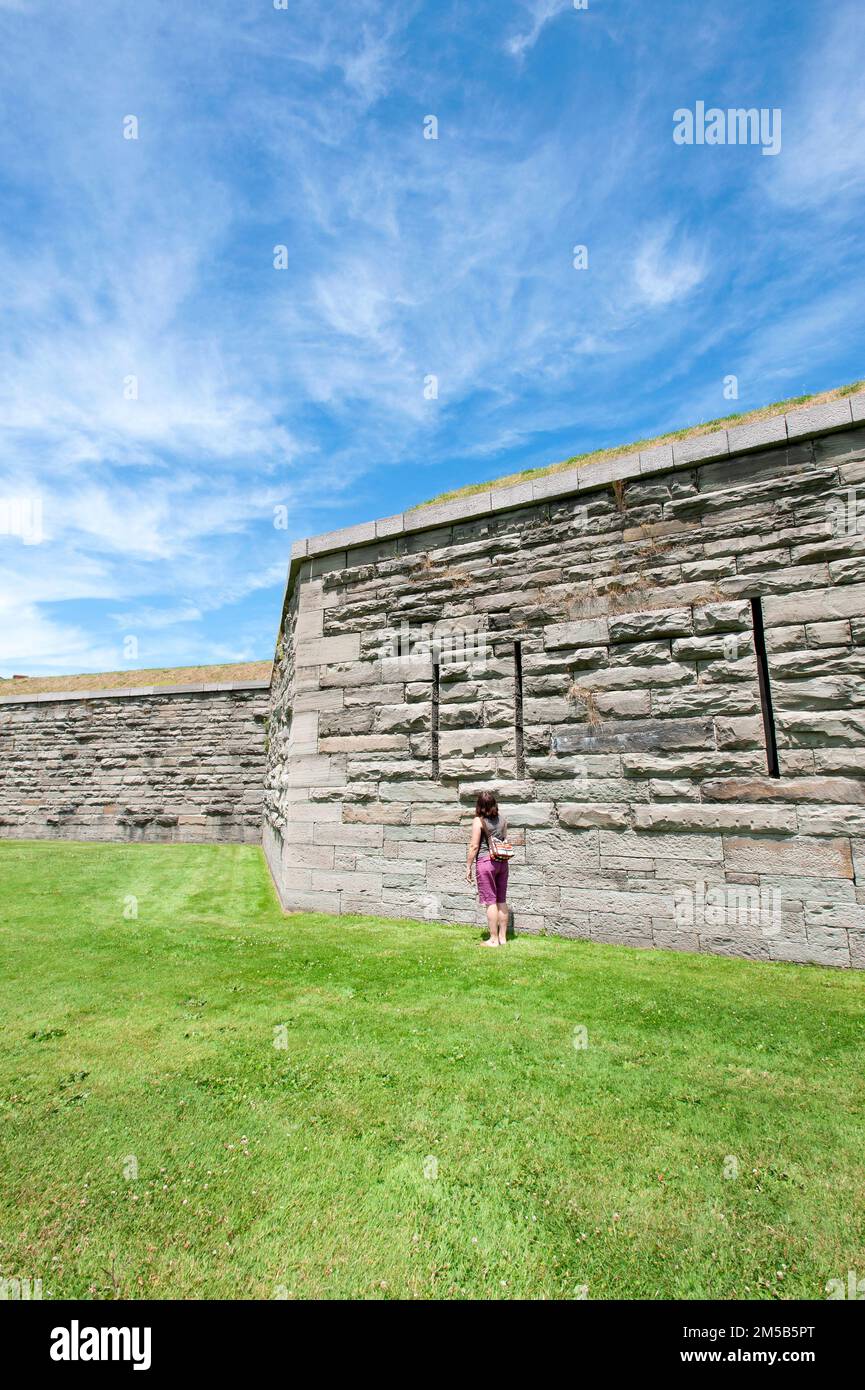 Oswego, New York, USA. Woman standing beside wall in Fort Ontario. Stock Photo