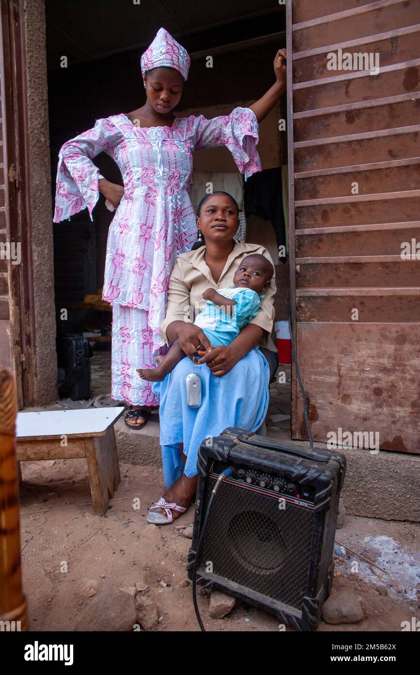 African family in traditional dress sitting next to a guitar amp