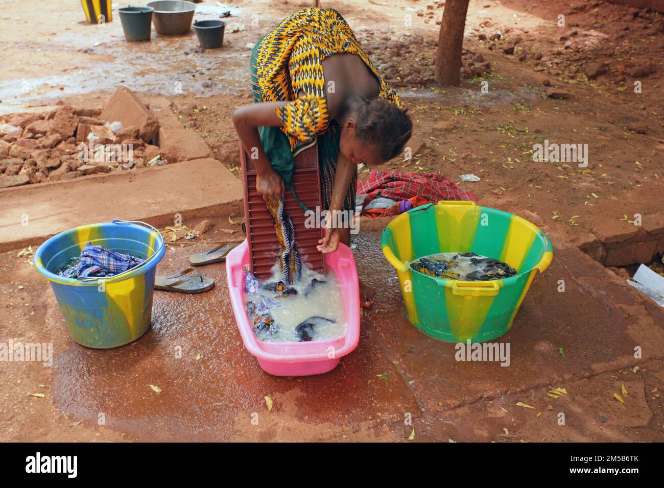 African woman wash clothes in bucket with an antique washboard Stock
