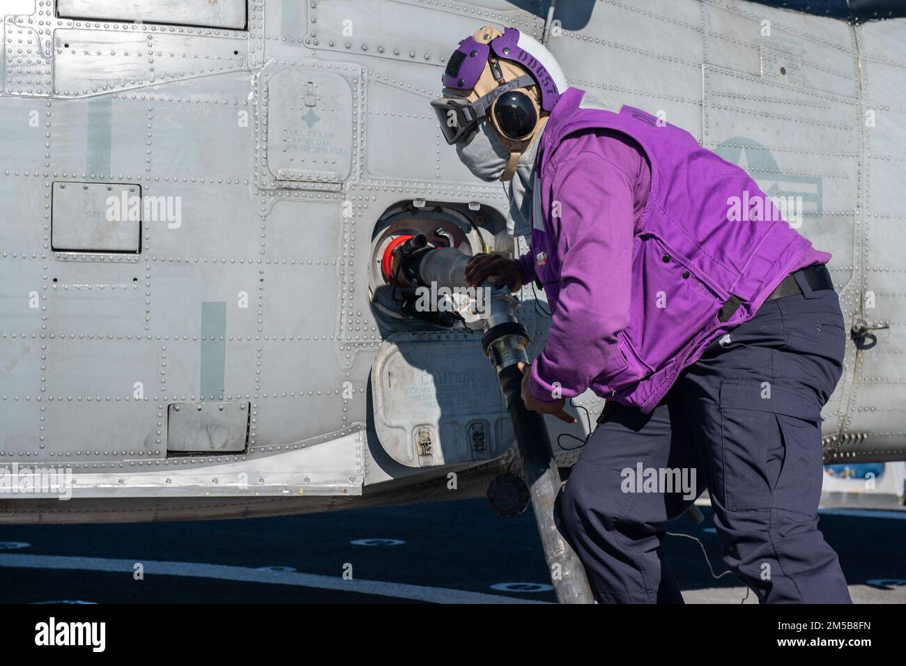 220218-N-HG846-2037 ADRIATIC SEA (Feb. 18, 2022) – Gas Turbine Systems Technician 2nd Class Demario Spencer, from Monroe, La., connects a fuel probe during helicopter refueling with a MH-60S Sea Hawk helicopter assigned to the “Dragon Slayers” of Helicopter Sea Combat Squadron (HSC-11) aboard Arleigh Burke-class guided-missile destroyer USS Mitscher (DDG 57), Feb. 18, 2022. Mitscher is deployed with the Harry S. Truman Carrier Strike Group on a scheduled deployment in the U.S. Sixth Fleet area of operations in support of naval operations to maintain maritime stability and security, and defend Stock Photo