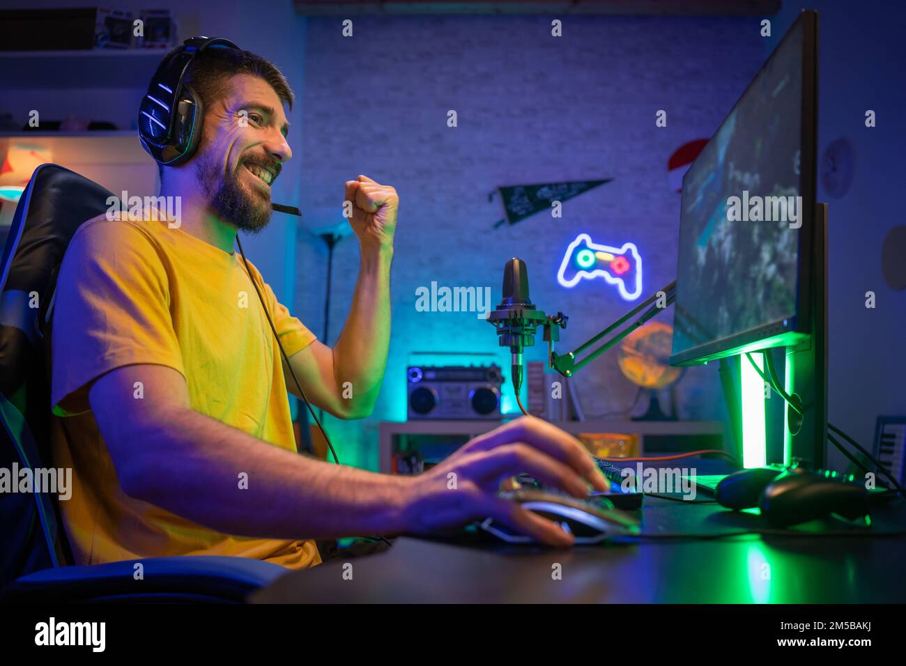 Professional Gamer winning and celebrating victory Online Video Game on Computer side view Stock Photo