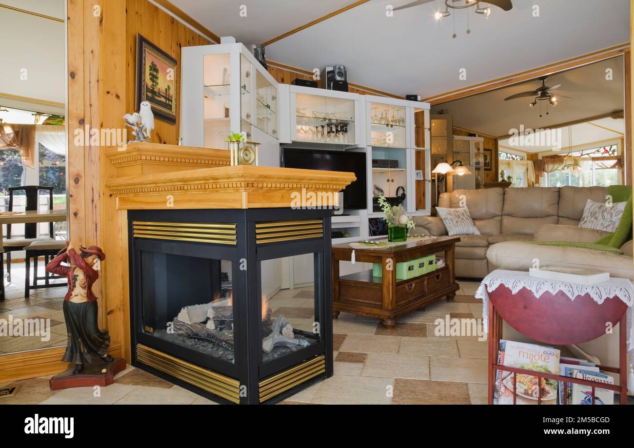 Propane gas fireplace between the dining room and living room with white gloss finish laminated wall unit inside 1987 Archimed style home. Stock Photo