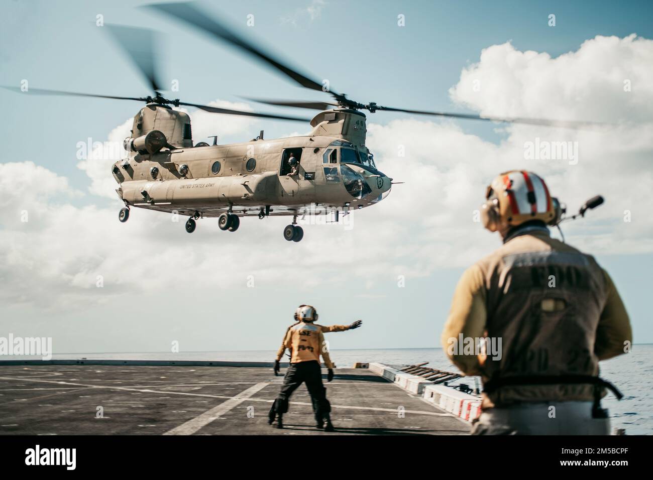 PACIFIC OCEAN (Feb. 18, 2022) U.S. Sailors assigned to amphibious transport dock USS Portland (LPD 27) signal to a U.S. Army CH-47F Chinook attached to 3rd Battalion, 25th Aviation Regiment, 25th Combat Aviation Brigade, while conducting deck landing qualifications, Feb. 18. Marines and Sailors of the 11th Marine Expeditionary Unit and Essex Amphibious Ready Group are underway conducting routine operations in U.S. 3rd Fleet. Stock Photo
