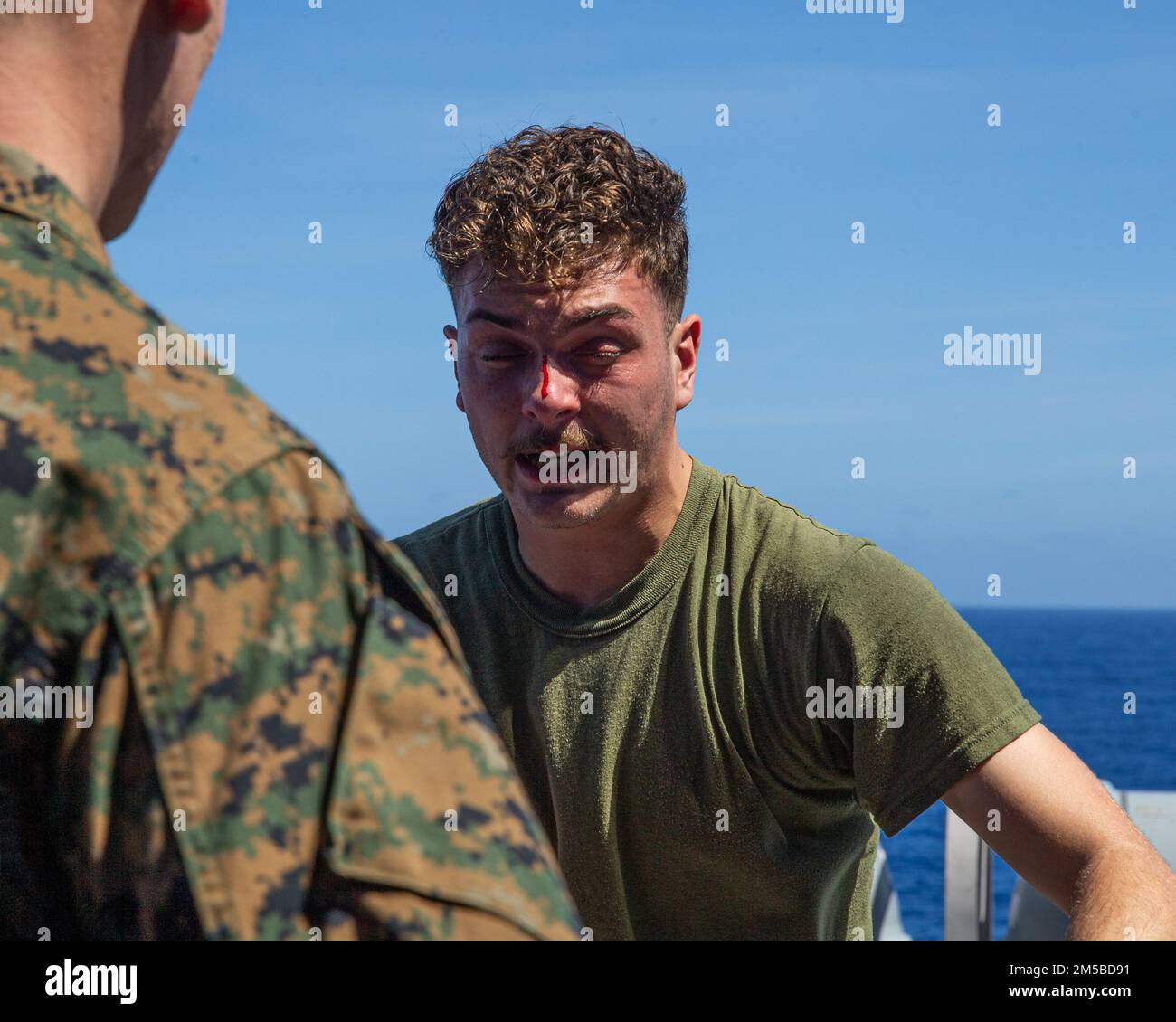 U.S. Marine Corps Lance Cpl. Mason Hamline, a radio operator with Battalion Landing Team (BLT) 1/5, 31st Marine Expeditionary Unit, catches his breath during an OC spray course, aboard USS Green Bay, Philippine Sea, Feb. 19, 2022. The 31st MEU is operating aboard the ships of the America Amphibious Strike Group in the 7th fleet area of operations to enhance interoperability with allies and partners and serve as a ready response to defend peace and stability in the Indo–Pacific Region. Stock Photo