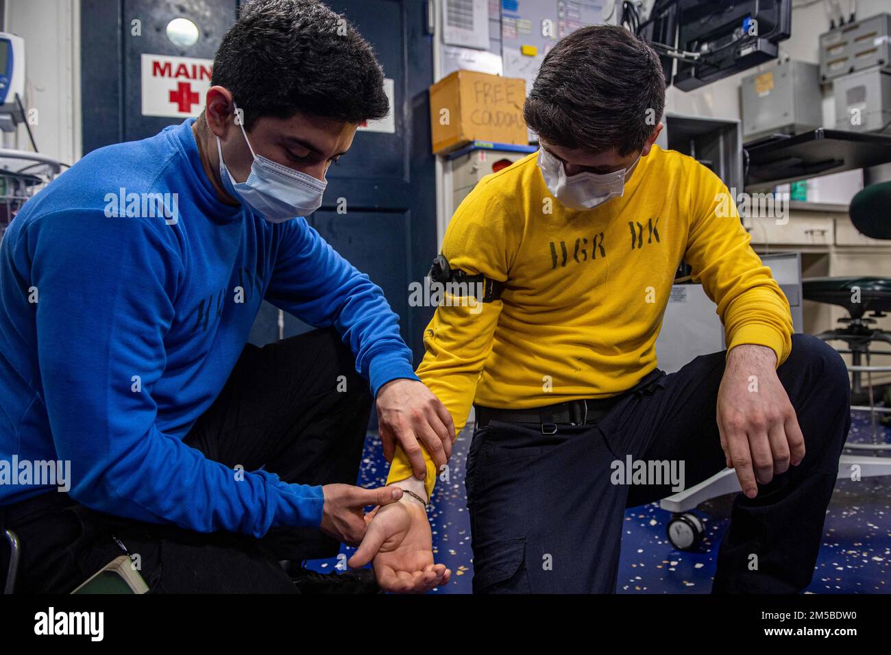 PHILIPPINE SEA (Feb. 20, 2022) Aviation Boatswain’s Mate (Handling) Airman Apprentice Damian Perez, left, from Oxnard, Calif., assigned to the forward-deployed amphibious assault ship USS America (LHA 6), checks the pulse of Aviation Boatswain’s Mate (Handling) 3rd Class Reynaldo Ruvalcaba, from San Benito, Texas, also assigned to America, after applying a tourniquet to his arm during a Tactical Combat Casualty Care exercise held in the ship’s medical bay. America, lead ship of the America Amphibious Ready Group, along with the 31st Marine Expeditionary Unit, is operating in the U.S. 7th Fleet Stock Photo