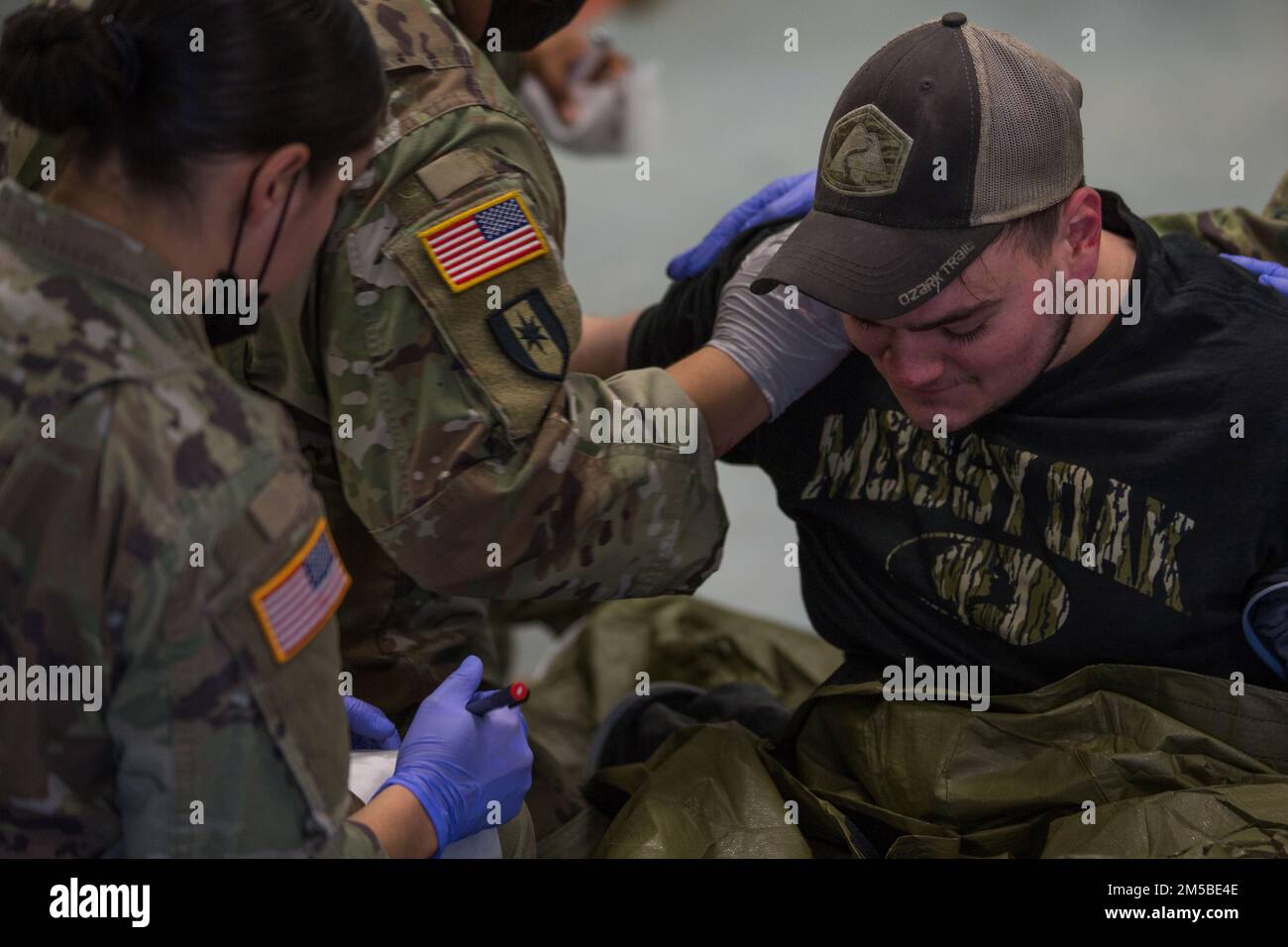 U.S. Soldiers assigned to 547th Medical Company Area Support medically assists a 'casualty' with simulated injures for a Mass Casualty exercise during Kosovo Forces (KFOR) 30 at the Joint Multinational Readiness Center, Hohenfels, Germany, Feb. 21, 2022. KFOR 30 is a multinational training event conducted to prepare units for their deployment to the Kosovo Regional Command East. Stock Photo